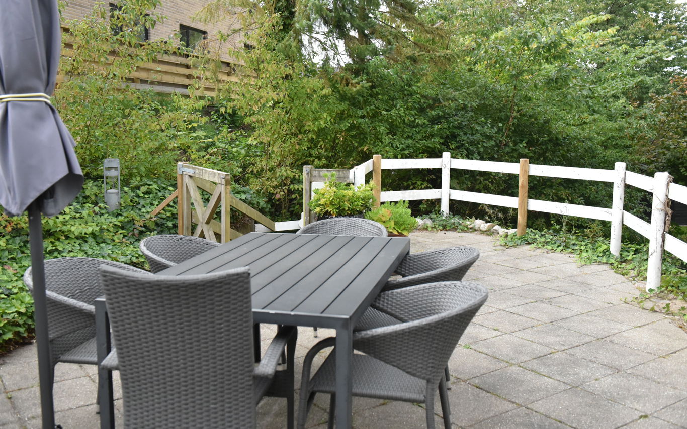 Terrasse med havemøbler og parasol hos Kristrupcentret