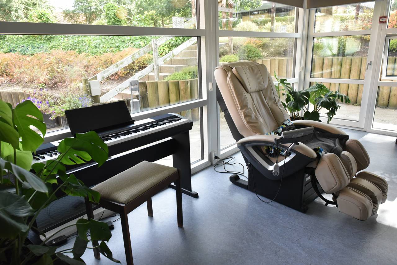 Stue med klaver og massagestol hos Kristrupcentret