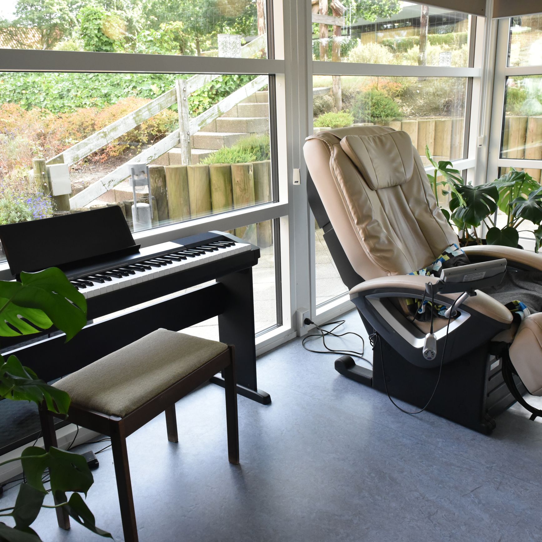 Stue med klaver og massagestol hos Kristrupcentret