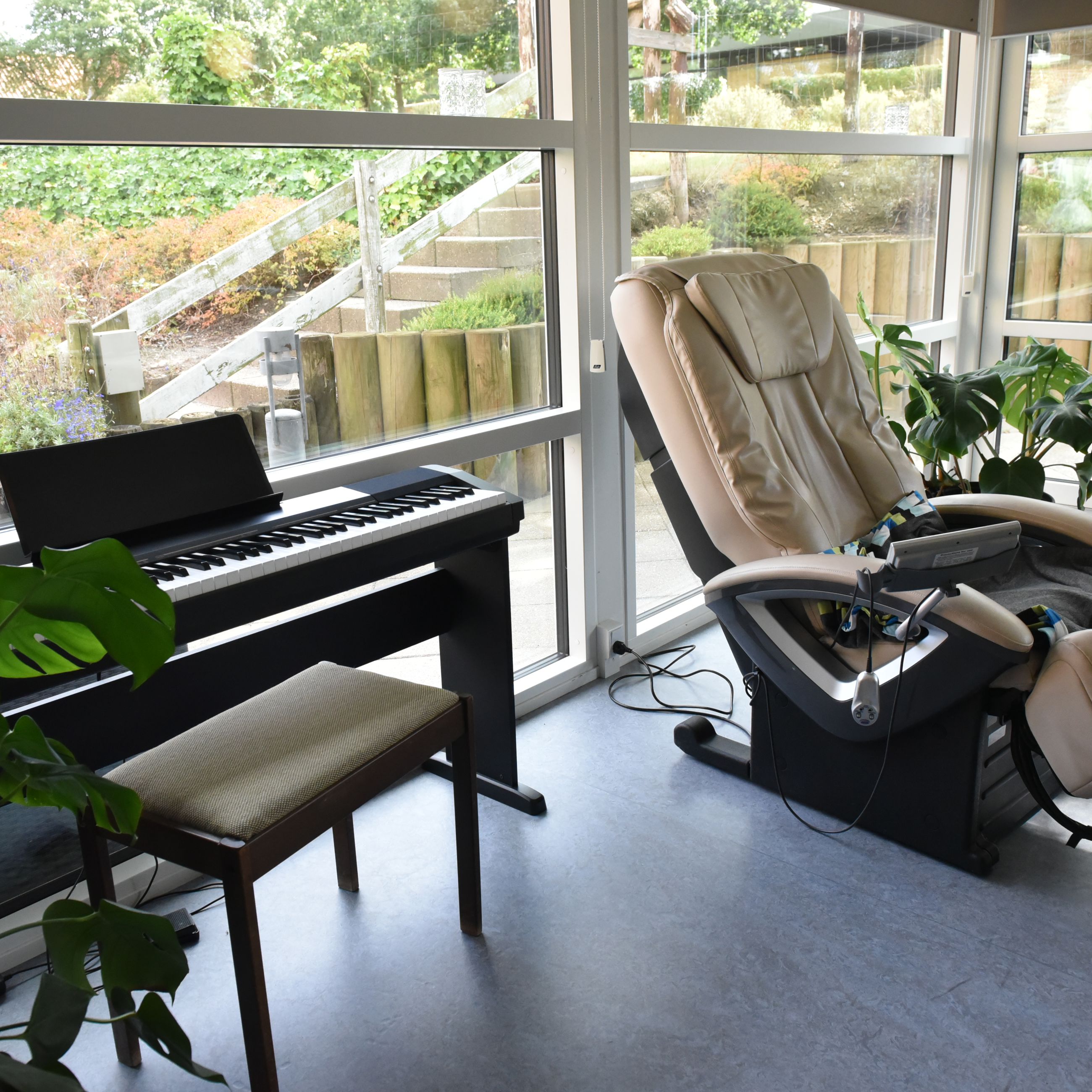 Stue med klaver og massagestol hos Kristrupcentret