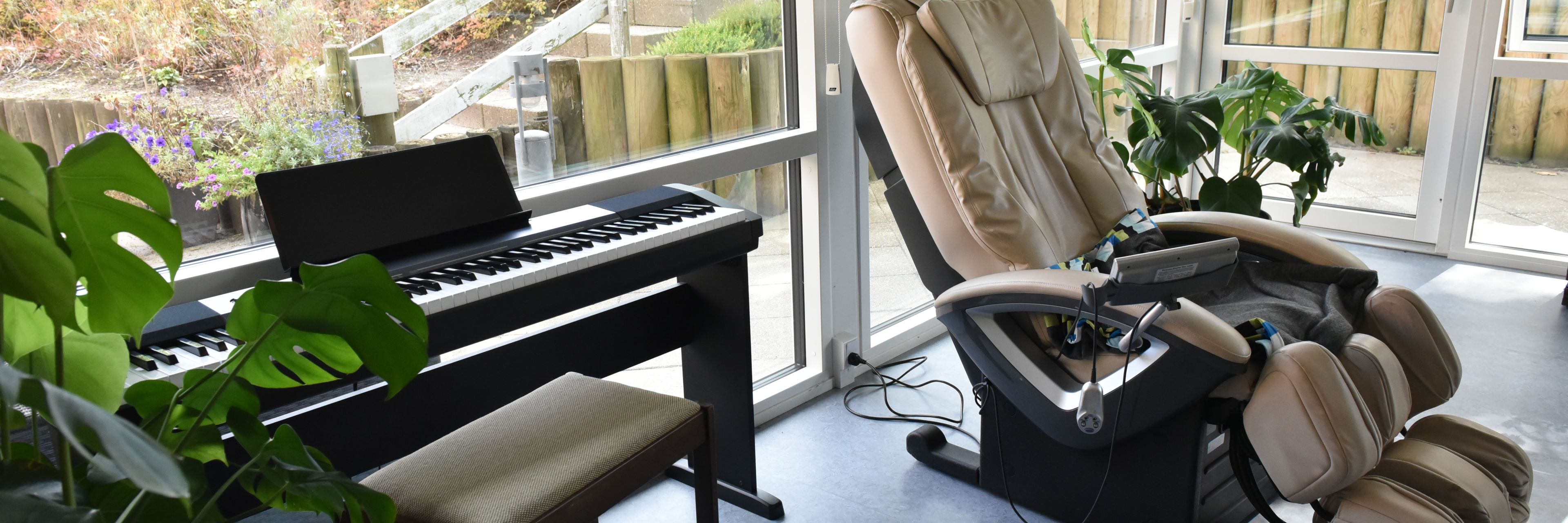 Stue med klaver og massagestol hos Kristrupcentret