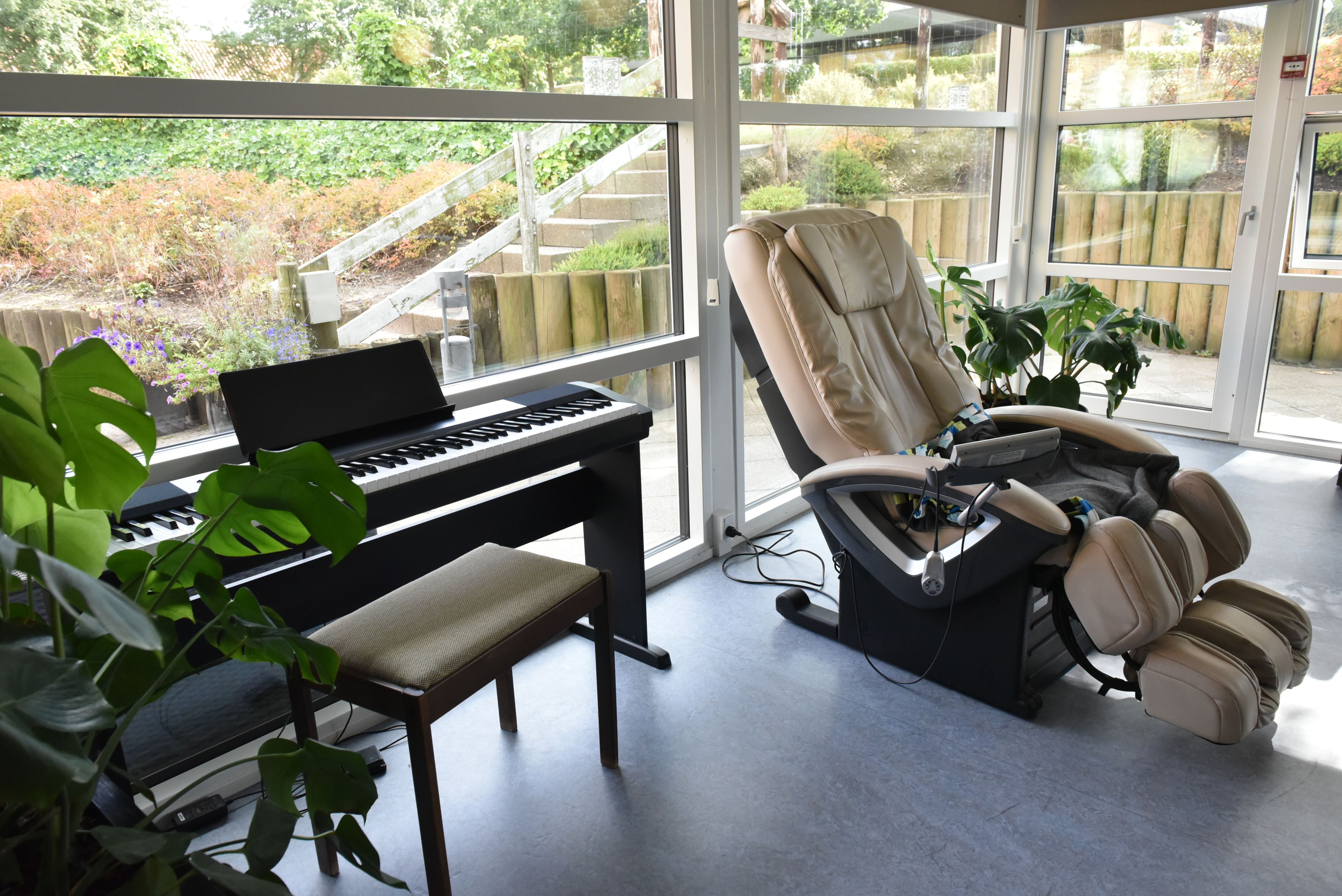 Stue med klaver og massagestol hos Kristrupcentret