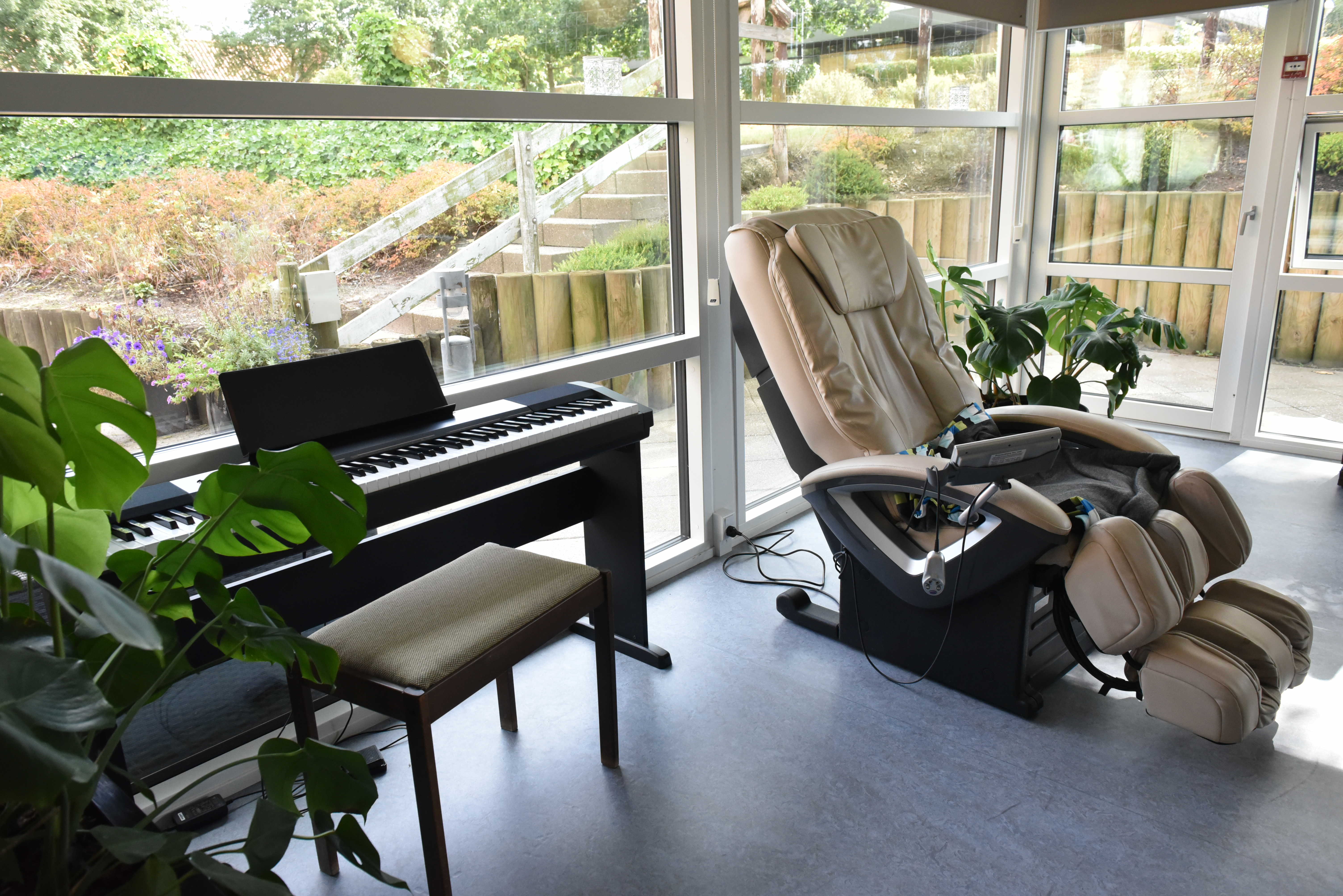 Stue med klaver og massagestol hos Kristrupcentret